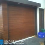 modern smooth wooden garage door with matching accents installed at Toronto home
